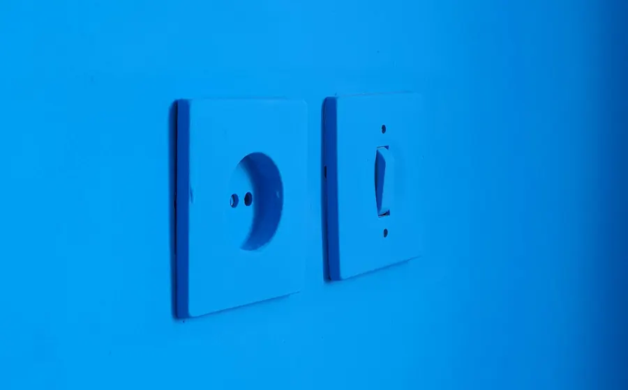 Enchufe e interruptor instalados en un muro azul