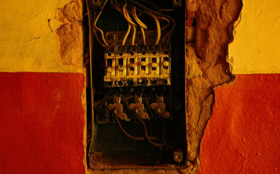 Caja eléctrica expuesta en un muro con el estuco roto