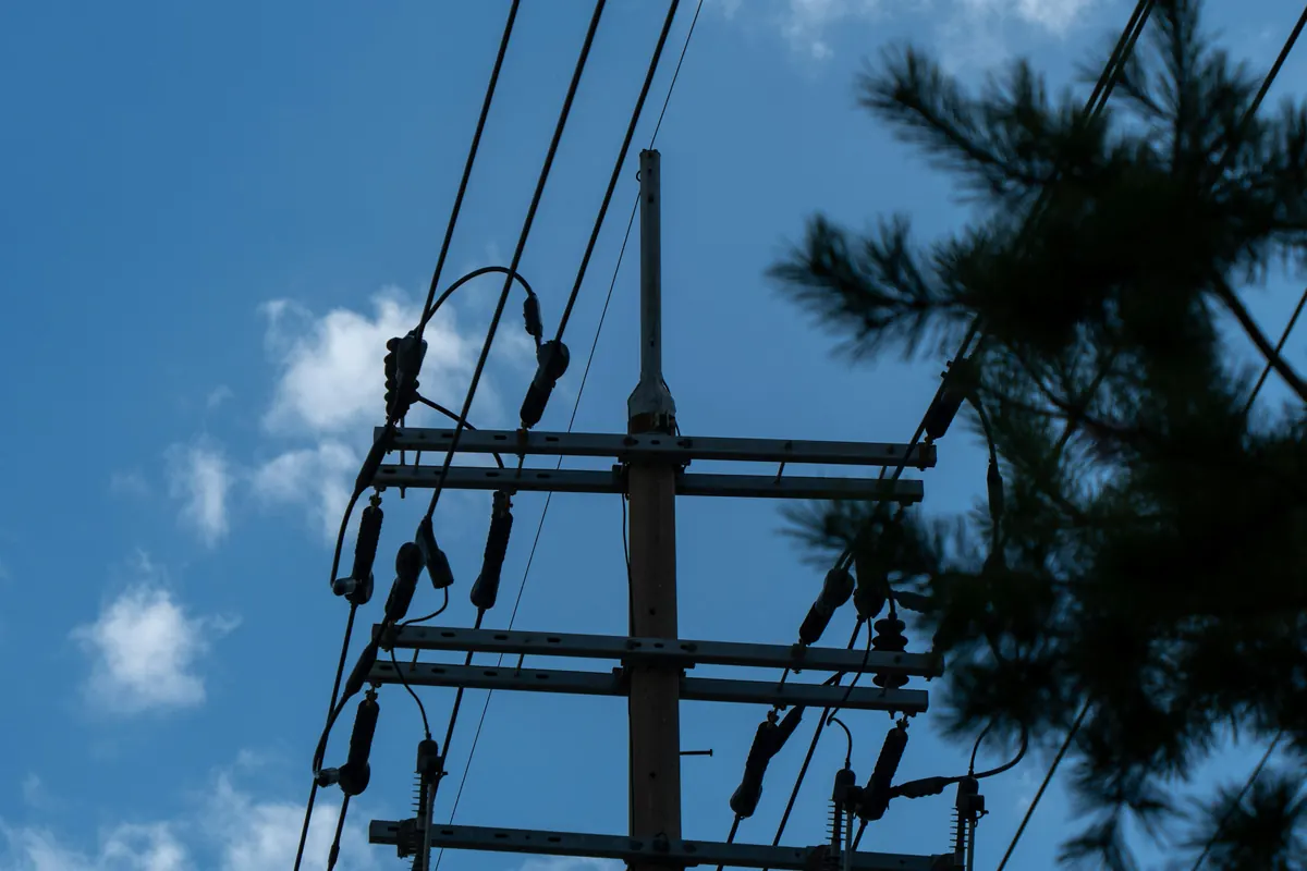 Postes y líneas eléctricas con un transformador contra el cielo